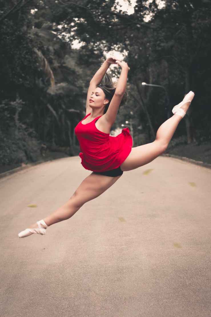 photo of ballerina split jumping in the middle of the road